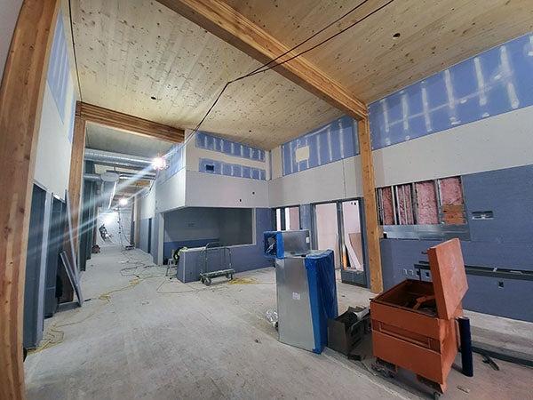 drywall being installed in a room with wood beams and a wood ceiling